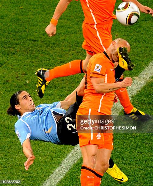 Netherlands' midfielder Demy de Zeeuw is kicked in the face by Uruguay's defender Martin Caceres during the 2010 World Cup semi-final football match...