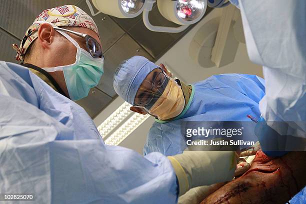 Navy Commander Joseph Strauss of Nesquehoning, Pennsylvania and Major Anton Lacap of Alameda, California, perform surgery on the leg of an Afghan man...
