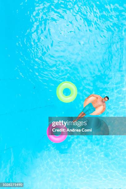 carefree man on inflatable donut - man on float stock pictures, royalty-free photos & images