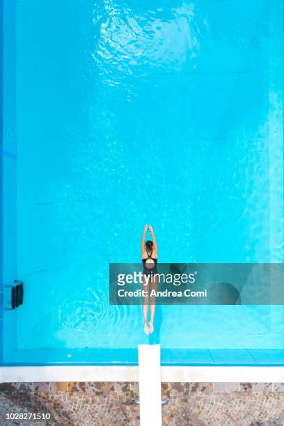 aerial view of woman diving into swimming pool - aerial pool stock-fotos und bilder