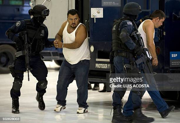 Two alleged drug traffickers, members of the Sinaloa Cartel, are escorted to be presented to the press in Mexico City, on July 12 after the Mexican...