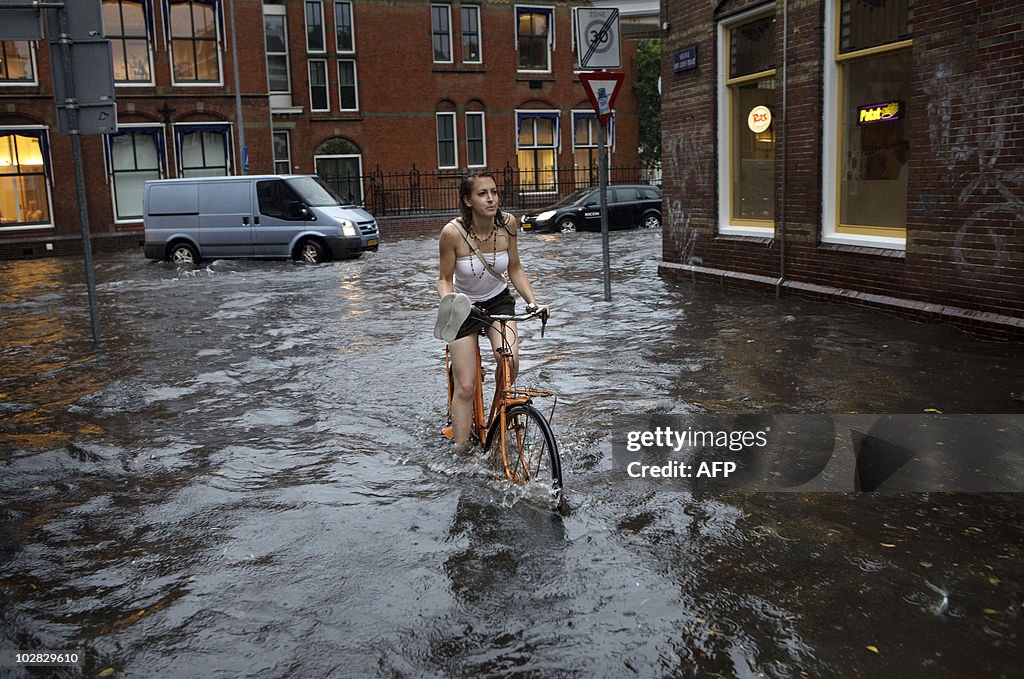 A woman rides a bike in a flooded street