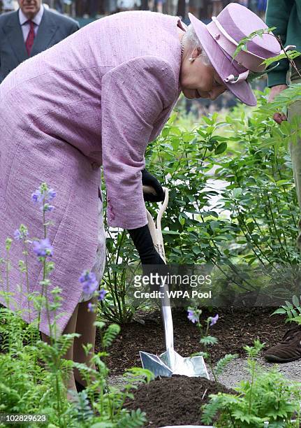 Queen Elizabeth II plants a tree during her visit to officially open a Visitor Centre at the Royal Botanic Garden Edinburgh on July 12, 2010 in...