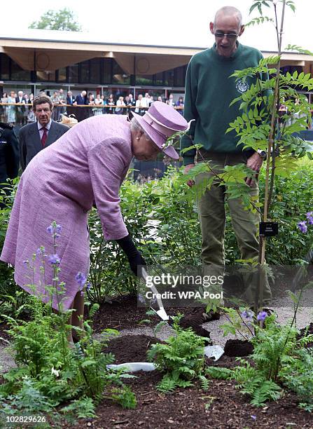 Queen Elizabeth II plants a tree during her visit to officially open a Visitor Centre at the Royal Botanic Garden Edinburgh on July 12, 2010 in...