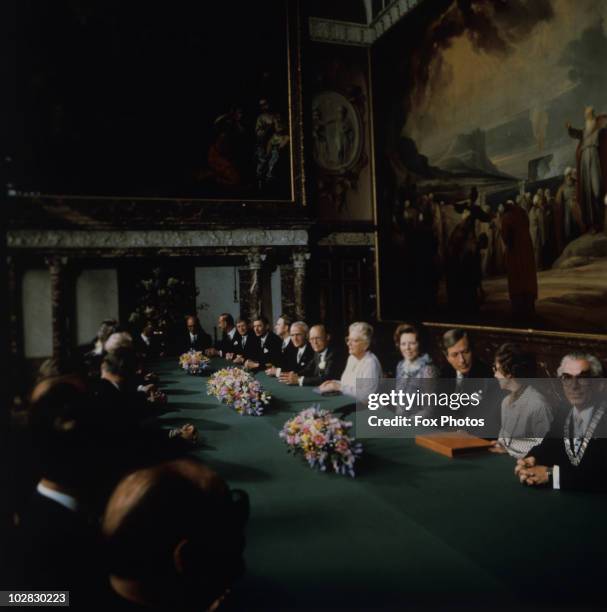 Crown Princess Beatrix of the Netherlands, Queen Juliana of the Netherlands , and Prince Claus of the Netherlands seated at a long desk at a council...