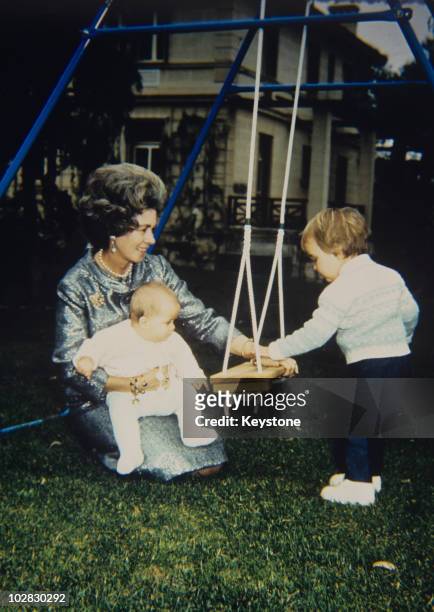 Queen Frederica of Greece with a baby and a small child by a swing, 1981.