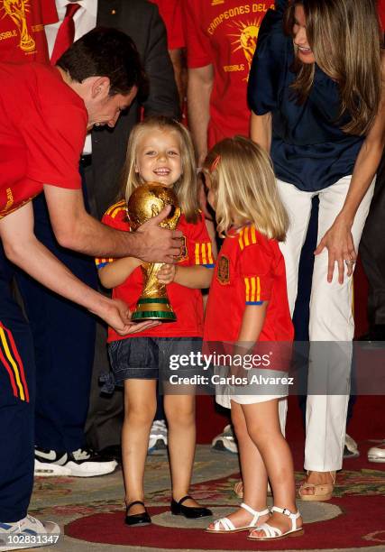 Princess Leonor of Spain holds the trophy with goalkeeper and captain Iker Casillas, watched by Princess Sofia and Princess Letizia of Spain while...