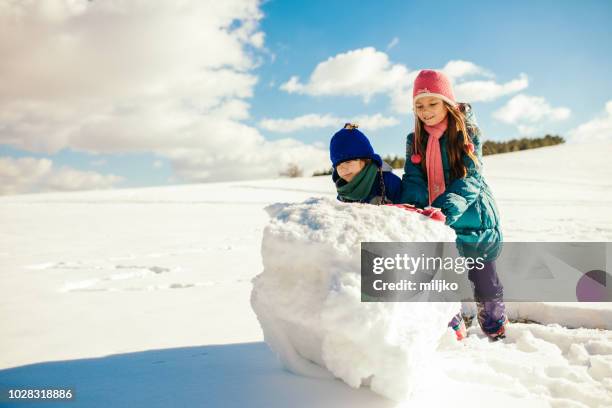 boy and girl making snowball for snowman - de rola imagens e fotografias de stock