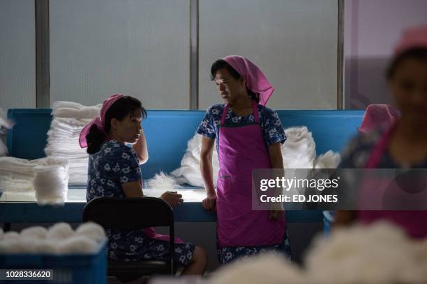 Workers stand before piles of silk during a guided tour for visiting foreign media to the Kim Jong Suk textile factory in Pyongyang on September 7,...