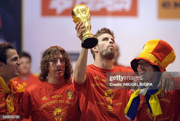 Spain's defender Gerard Pique holds up the trophy next to team mates on a stage set up for the Spanish team victory ceremony in Madrid on July 12,...