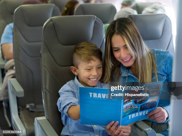 mother and son traveling by plane and reading a travel guide - guidebook stock pictures, royalty-free photos & images