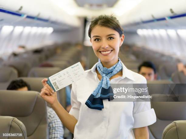 flight attendant in an airplane holding a boarding pass - flight attendant portrait stock pictures, royalty-free photos & images