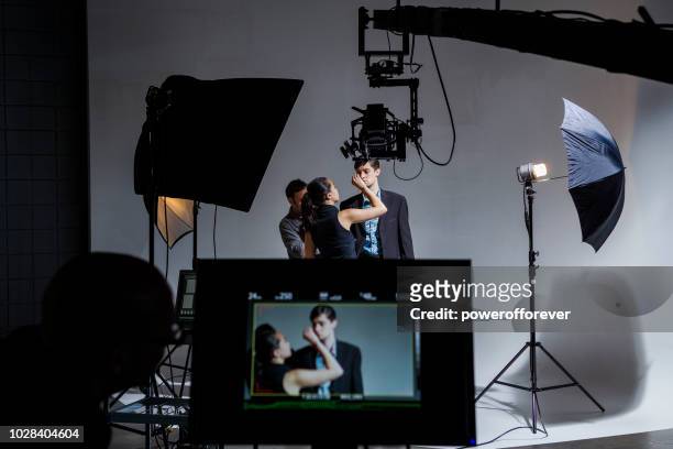 makeup artist and wardrobe stylist working on actor behind the scenes on a film set - movie crew stock pictures, royalty-free photos & images