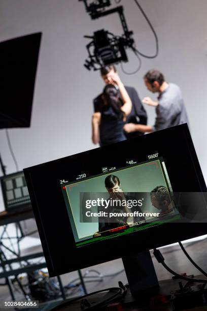 makeup artist and wardrobe stylist working on actor behind the scenes on a film set - movie actor stock pictures, royalty-free photos & images