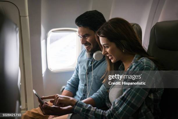paar reizen met het vliegtuig en het gebruik van hun mobiele telefoon aan boord - couple airplane stockfoto's en -beelden