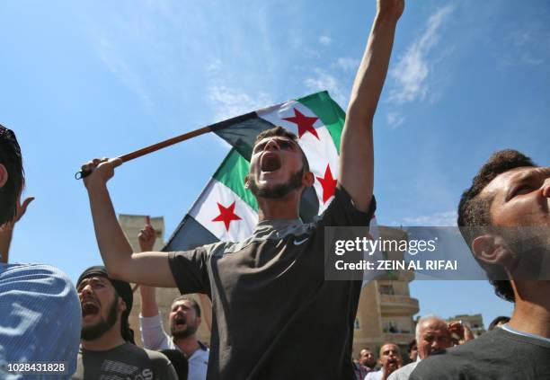 Syrian protesters wave the flag of the opposition as they demonstrate against the regime and its ally Russia, in the rebel-held city of Idlib on...