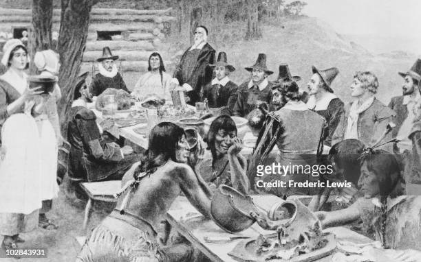 Depiction of early settlers of the Plymouth Colony sharing a harvest Thanksgiving meal with members of the local Wampanoag tribe at the Plymouth...