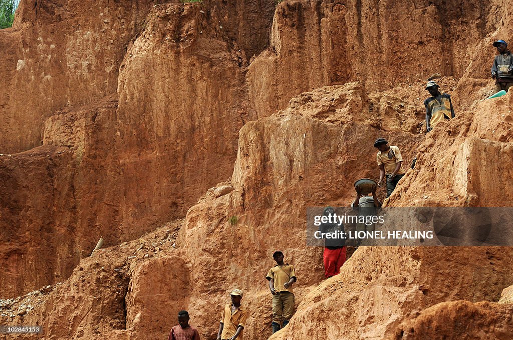 Workers stand on a muddy cliff as they w