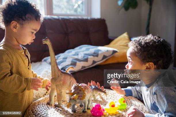 Toddler brothers playing with dinosaur and rubber duck toys