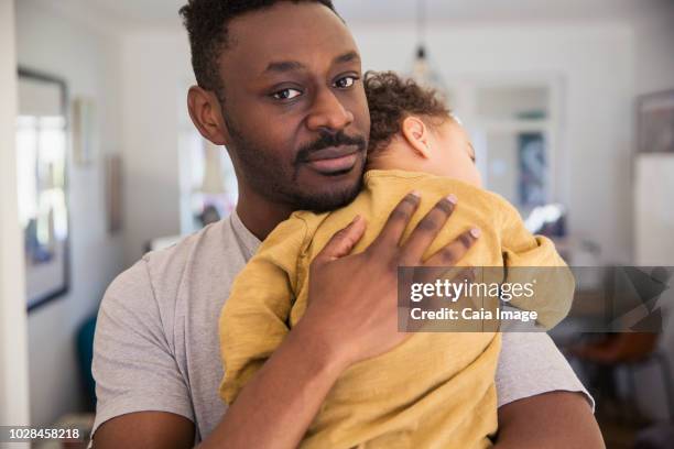 Portrait affectionate father holding tired baby son