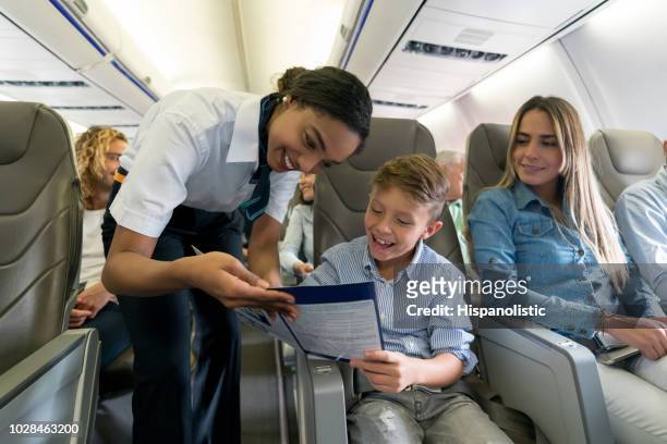 friendly air hostess helping a boy in an airplane - crew stock pictures, royalty-free photos & images