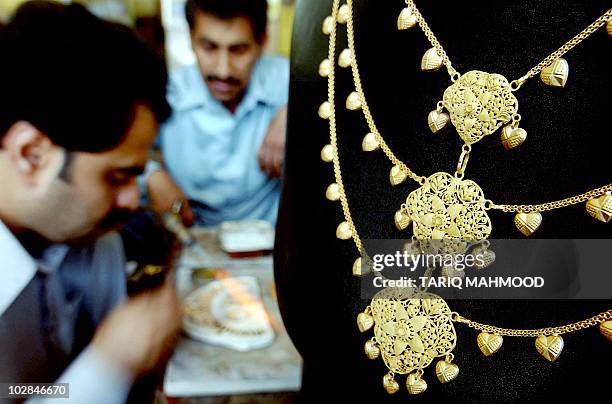 Pakistani jewellery prepares a necklace at a gold shop in Peshawar, 18 April 2006. The gold price has risen in Pakistan over the last several weeks...