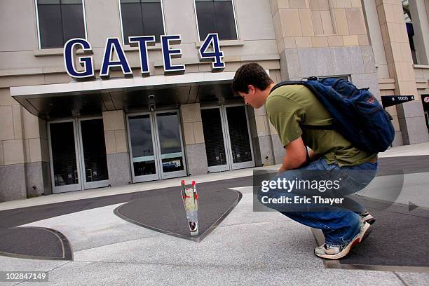 Tyler Bauer looks at a candle and two roses placed at Gate 4 at Yankee Stadium, after the death of George Steinbrenner July 13, 2010 in the Bronx...