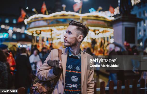 stylish young man at a carnival/funfair standing in front of a carousel - glasgow scotland stockfoto's en -beelden