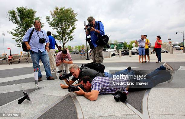 Members of the media photograph a candle and two roses placed at Gate 4 of Yankee Stadium, after the death of George Steinbrenner July 13, 2010 in...