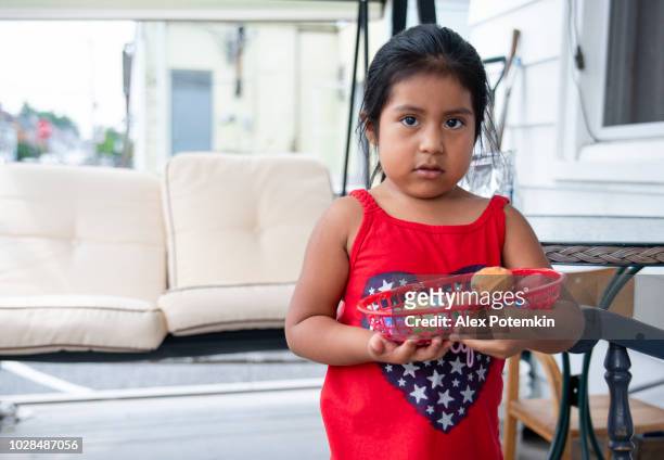 the little latino mexican-american girl holding the plate with fruits at the porch of his house - hot mexican girls stock pictures, royalty-free photos & images