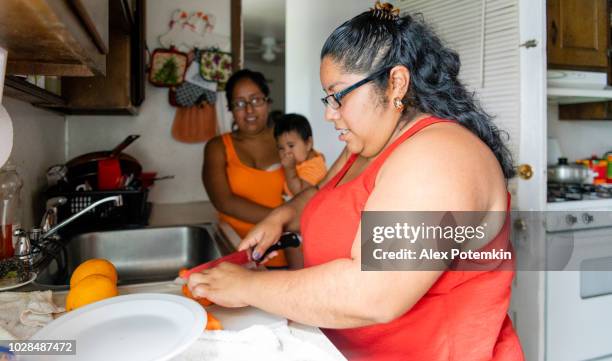 the body-positive beautiful mexican-american woman making fruit salad in the domestic kitchen - alex potemkin or krakozawr latino fitness stock pictures, royalty-free photos & images