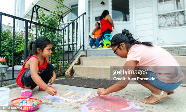 two little latino mexican-american girls, sisters, drawing with chalk at the porch of his house in pennsylvania - hot mexican girls stock pictures, royalty-free photos & images