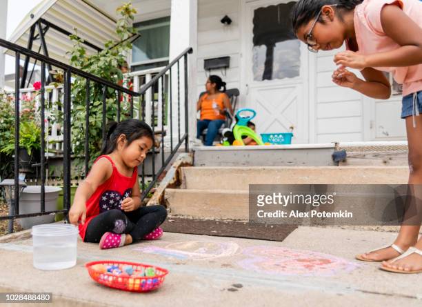 zwei kleine latino mexikanisch-amerikanischen mädchen, schwestern, zeichnen mit kreide auf der veranda seines hauses in pennsylvania - hot mexican girls stock-fotos und bilder