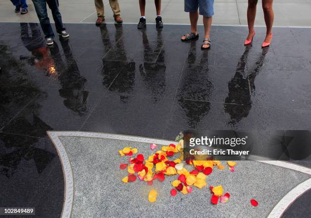 Fan Mary Byrne of Saddlebrook, New Jersey, and members of the media look at rose petals and a rose in front of Gate 4 at Yankee Stadium, after the...