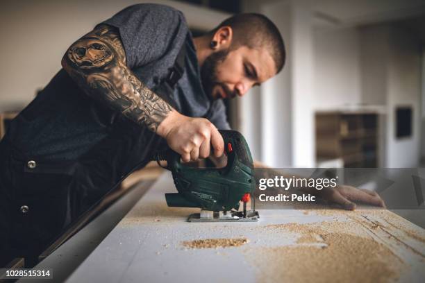 getatoeëerde handy man boren plank en tot vaststelling van de nieuwe houten tafel - handy man stockfoto's en -beelden