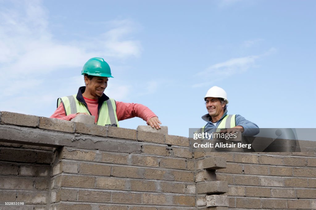 Two bricklayers building a wall