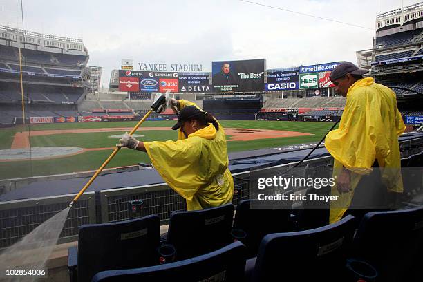 Workers clean seats as a memorial for former Yankee's Owner George Steinbrenner is displayed on the large screen July 13, 2010 at Yankee Stadium in...