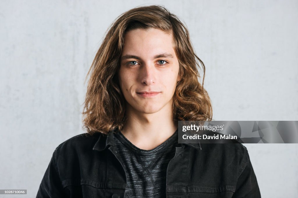 Portrait of a long haired young man wearing a black jacket.