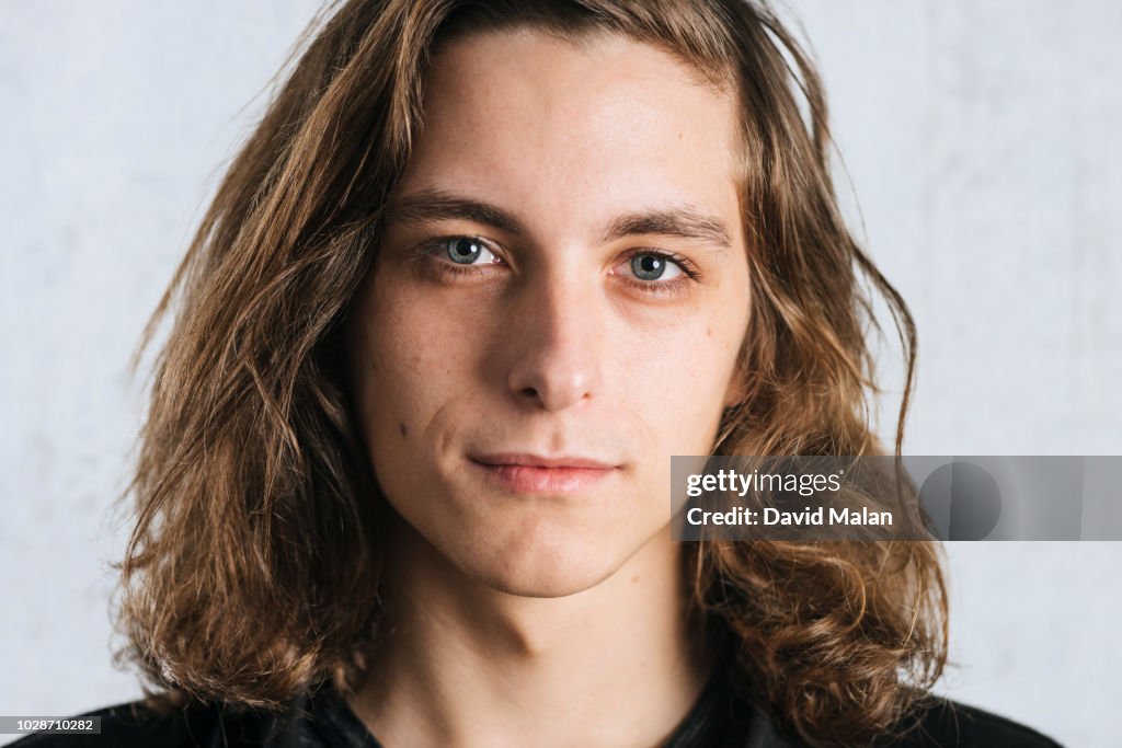 Close up portrait of a blue eyed, long haired, young man.