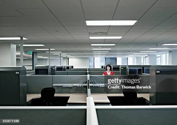 businesswoman standing alone in empty office - cubicle photos et images de collection