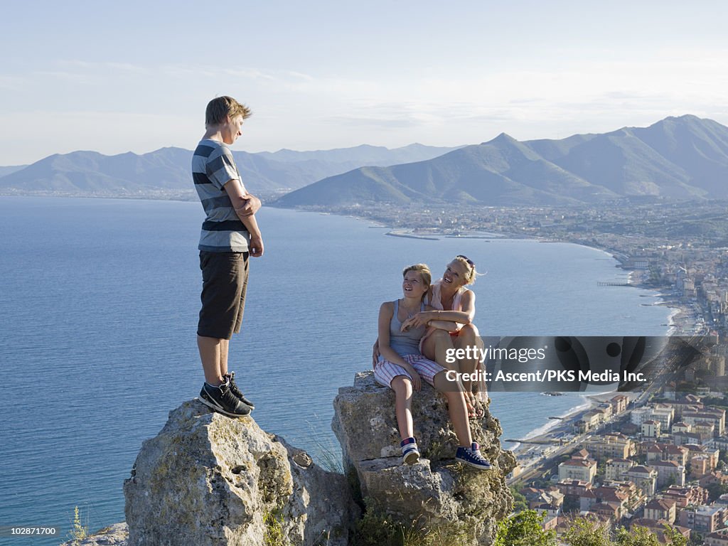 Mother and teenage kids resting on rocks