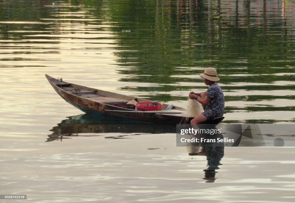 Fisherwoman fishing at dawn on the Thu Bon river, Hoi An, Vietnam