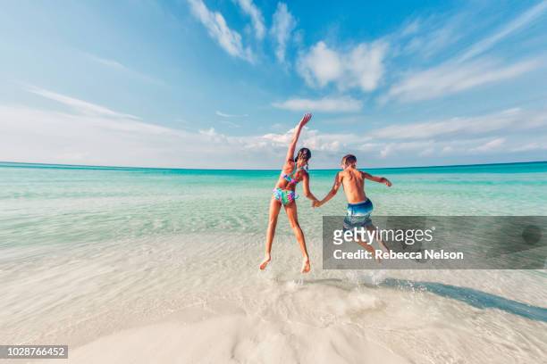 boy and girl jumping in the surf of the gulf of mexico - pretty girls in swimsuits ストックフォトと画像