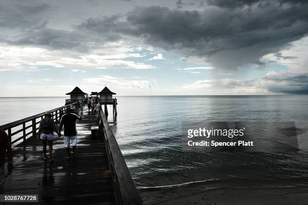 People walk along the Naples Pier in the evening light on September 7, 2018 in Naples, Florida. Despite being largely clear of the red tide that has...