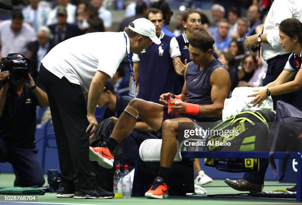 Rafael Nadal of Spain talks to the trainer as he is forced to retire due to injury in his men's singles semi-final match against Juan Martin del...