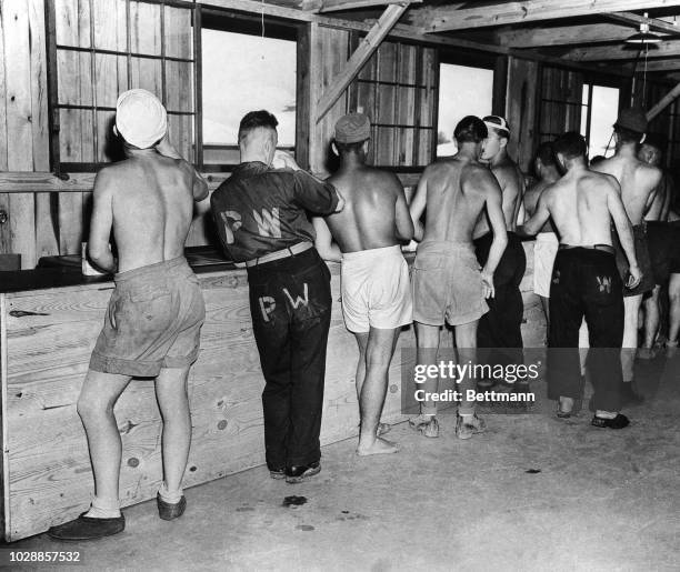 German war prisoners having ice cream and other refreshments in the camp's canteen. They are able to purchase through the use of coupon books...
