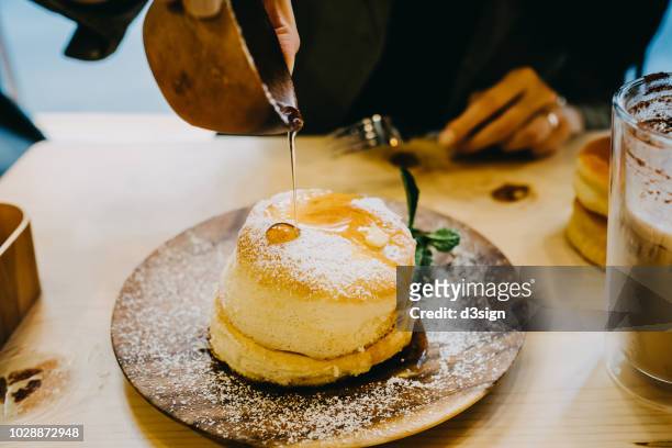 close up of woman drown the souffle pancake in maple syrup - maple syrup pancakes fotografías e imágenes de stock