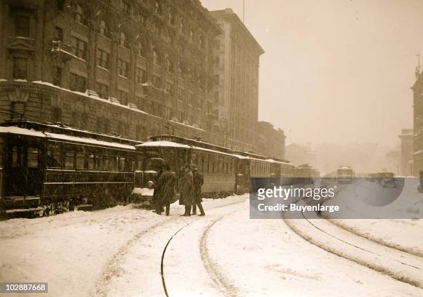Group of men approach a trolley stuck on the rail line, while other cars are lined up on the city streets during the Knickerbocker blizzard,...