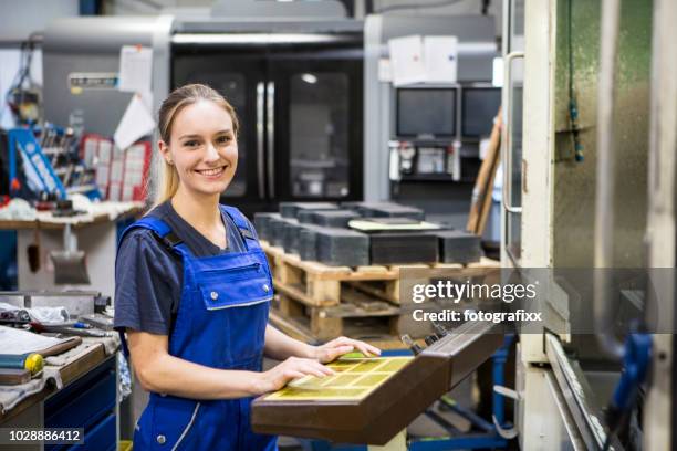 porträt: lachen junge, blonde frau vor der cnc-maschine - fräsen stock-fotos und bilder