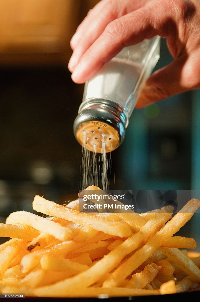 Pouring salt on french fries